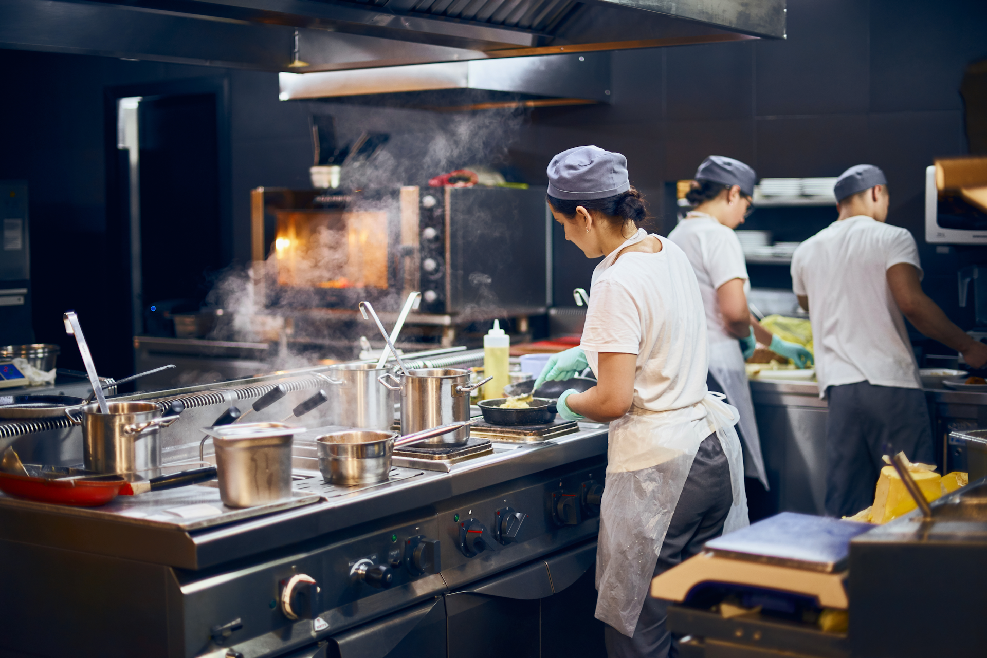 Three people working in a professional kitchen.