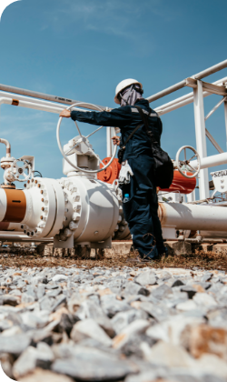 A person turning a wheel on a pipeline.