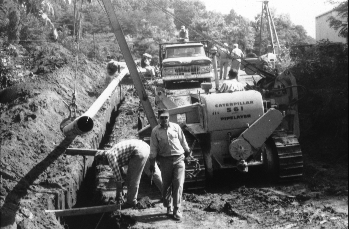 Workers and heavy equipment installing a large pipeline.