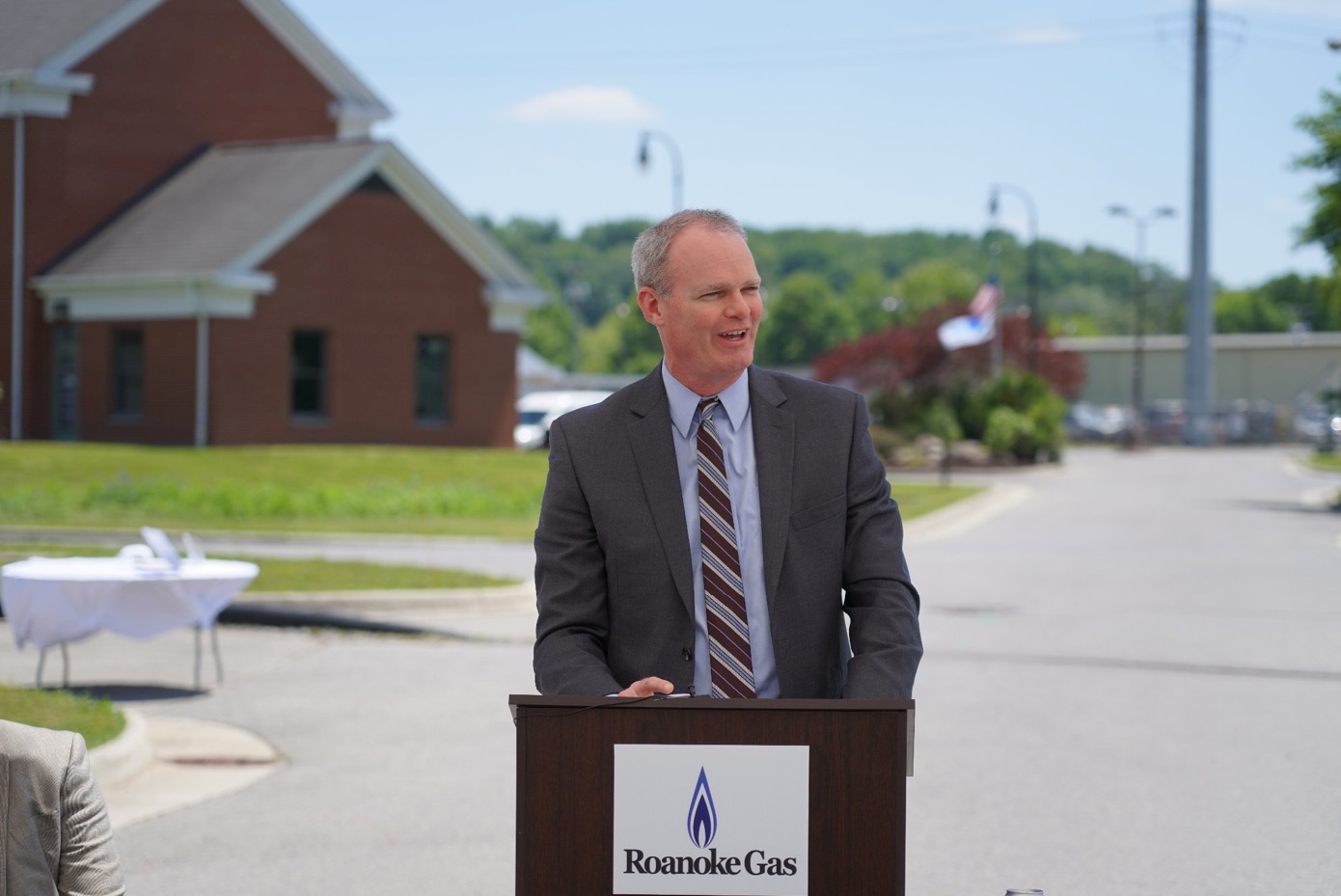 A man standing outside at a podium with the Roanoke Gas logo on it.